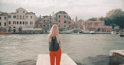 Slow Motion 4K view on Woman tourist Traveler in Venice white sunhat walking and shooting with her phone camera on old streets with canals in Italy. Girl traveling to famous popular landmark