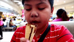 Handheld video shot of a young Asian boy eating ice cream on a cone
