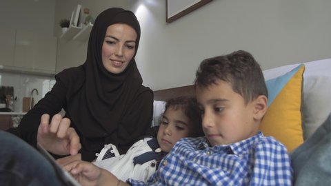 Young Arab mother in traditional dress is engaged in preschool activities
