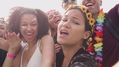 Group Of Young Friends Dancing Behind Barrier Taking Selfie At Outdoor Music Festival 