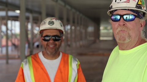 Construction workers wearing sunglasses giving thumbs up with one worker in foreground