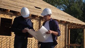 teamwork. concept building constructing architect slow lifestyle motion video. two men builder in helmets study the house plan. two architects working on the construction of a frame house business