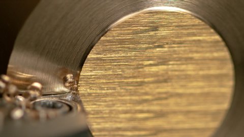 SLOW MOTION, MACRO, DOF: Sharp lathing tool creates curly shavings while cutting into a brass cylinder. Detailed view of a CNC machine creating a groove at the edge of a small and shiny brass rod.