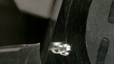 SLOW MOTION, MACRO, DOF: Shiny piece of aluminium is spun by a CNC machine to shave its sharp edges. Twisted excess metal chips come off a small steel workpiece during an automated lathing process.