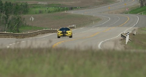Dunvegan , Alberta / Canada - 06 20 2019: Ford Mustang drives by at high speed near Dunvegan Alberta on highway. Camera pans as car drives by.