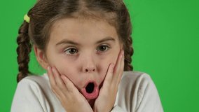 Little female is surprised, scared and hiding her face in the studio on green screen. She has two pigtails, dressed in a white sweater. Slow motion. Close up