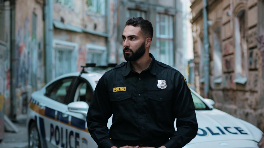 Portrait attractive young man cops stand near patrol car look at camera enforcement happy officer police uniform auto safety security communication control policeman close up slow motion Royalty-Free Stock Footage #1035105701