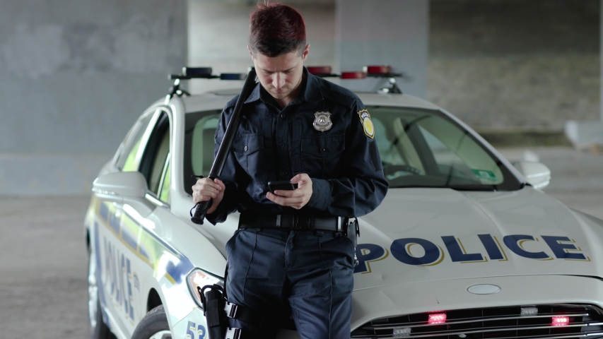 Policeman cops stand near patrol car use phone accepting emergence call enforcement talk officer police uniform auto safety security communication control policeman slow motion