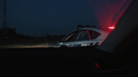 Police pull over at night. View in the car side rear mirror of police car outrace arrive and pull over the driver on the highway.