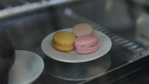 A close-up of a plate with three colo rful macaroons behind a shop window