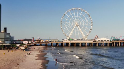 Atlantic City , New Jersey / United States - 06 03 2019: Atlantic City, New Jersey with Ferris Wheel, beachfront and the boardwalk with casinos and hotels on the beachfront, aerial view