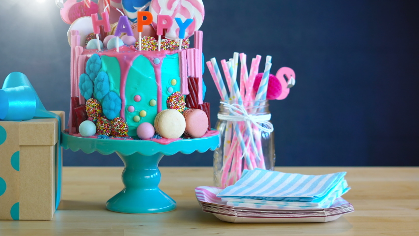 On-trend candyland fantasy drip cake with gift in blue theme birthday party setting.