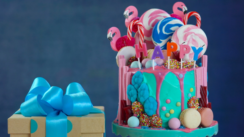 On-trend candyland fantasy drip cake with gift in blue theme birthday party setting.