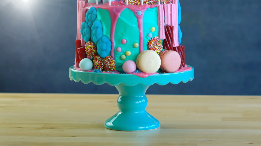 On-trend candyland fantasy drip cake with gift in blue theme birthday party setting.
