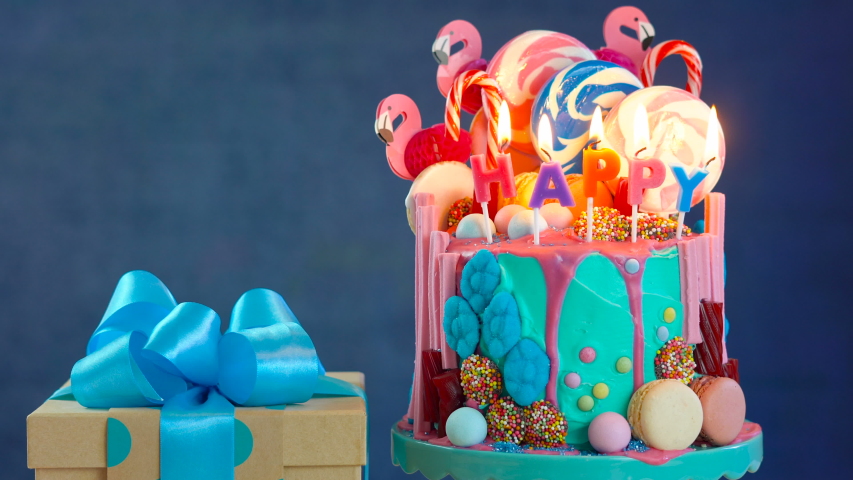 On-trend candyland fantasy drip cake with gift in blue theme birthday party setting.