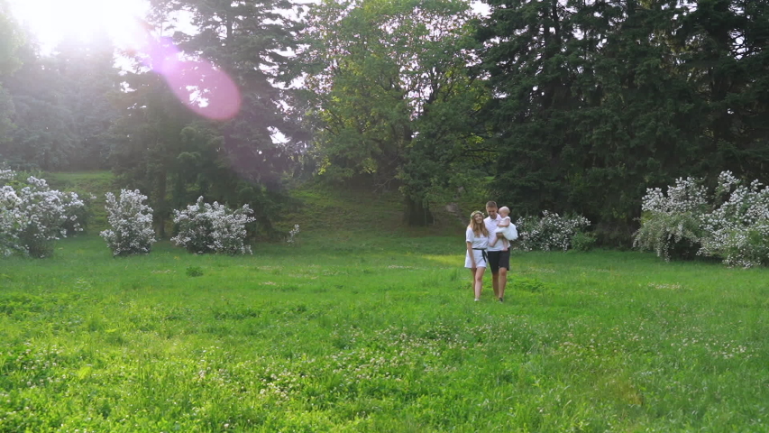 A family walks in the park. Happy family vacation. Panoramic Camera Shot.