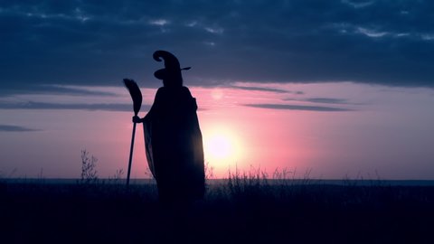 woman in halloween costume witch says the spell on the hill sky with yellow sun slow motion outdoors autumn background