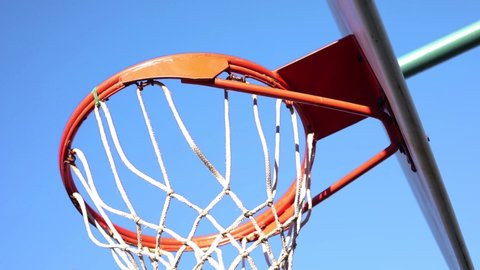 Basketball going in the basket on an outdoor basketball hoop.