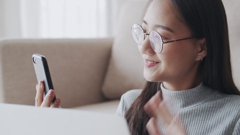 Portrait of a beautiful Asian woman using phone, asia girl chatting with a friend through a video call  in living room at her home