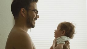 Slow motion of man lifting his baby daughter up at home