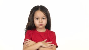 Little girl in red T-shirt shows emotion, crosses hands posing at white background. Little girl crosses hands with offended or indignant . Slow motion