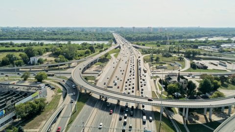 Transportation and Infrastructure: Aerial View of Road Traffic in Warsaw, Poland. Highway Interchange and Junction with Cars and Trucks. Big City Skyline and River at the Background. 4K Fly Over shot