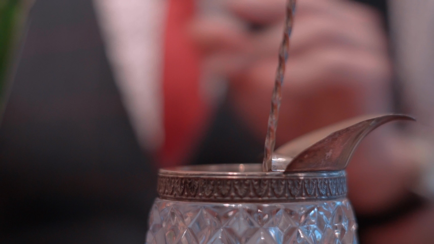 Gentleman barman preparing a glass of whisky with sphere ice, ice mold