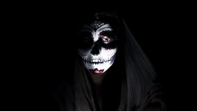 Halloween mask CALAVERA CATRINA. A girl in a blinking and frightening light. Mexican day of the dead. Portrait of a young woman with scary multi-colored makeup for Halloween on a dark background. 4K - Powered by Shutterstock - Get 15% off with code: PIKWIZARD15