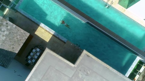 Overhead shot of girl swimming in private rooftop pool 