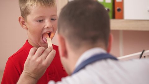 Little boy having throat examination with tongue depressor. Otolaryngology. Pediatric concept