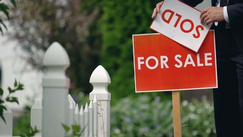 Real estate agent puts sold inscription on for sale signboard, successful deal