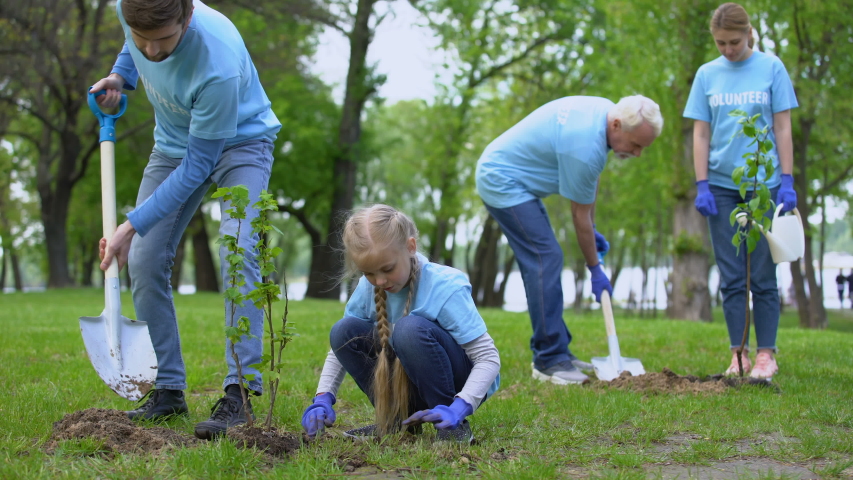 Family environmental volunteers planting trees smiling each other, reforestation Royalty-Free Stock Footage #1035149684