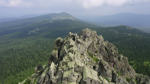 aerial view of russian national park Taganay. drone flying around a steep stony slope of mount overgrown with deep taiga forest of oldest mountain range in the world. beautiful scenery of wild nature