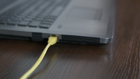 Disconnect the device. A woman`s hand with scissors cuts the wire running to computer.