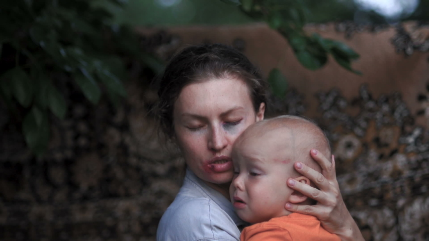 A male rapist orders not to cry a small child in the arms of the victim