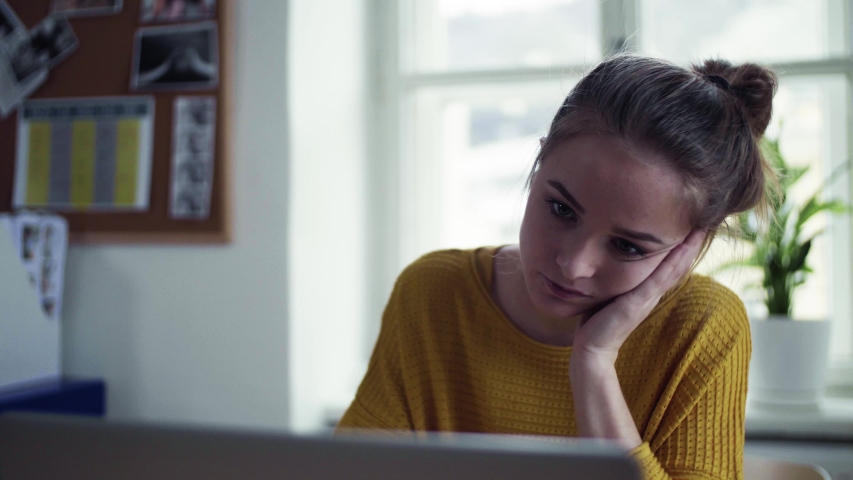 A young female student sitting at the table, using laptop when studying.