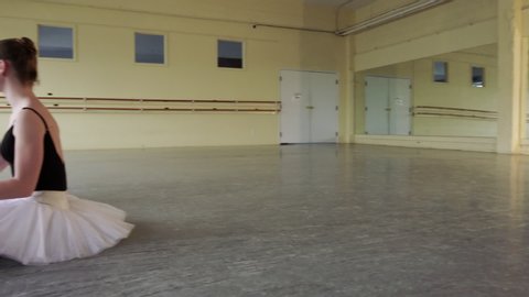 Ballerinas sitting on floor removing pointe shoes