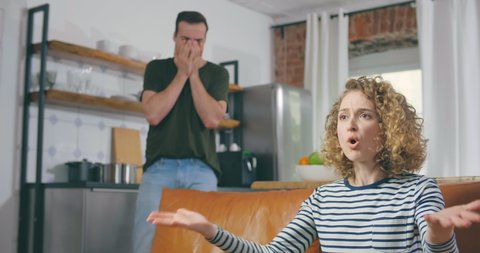 Depressed angry young woman shouting at her husband standing on background. Family conflict