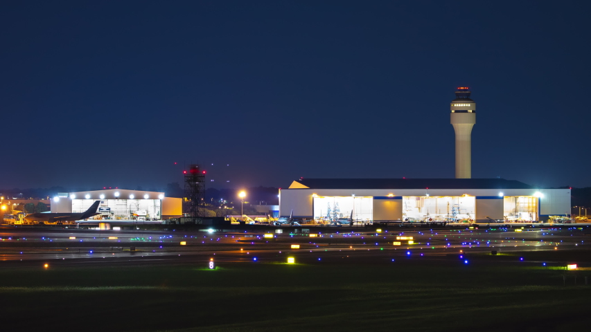 Generic Airport near Charlotte NC Night Airfield Action Exterior Timelapse with Streaking Lights from Moving Airplanes Landing Taxiing and Taking Off on a Clear Blue Sky Night in North Carolina