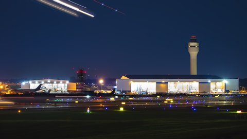 Generic Airport near Charlotte NC Night Airfield Action Exterior Timelapse with Streaking Lights from Moving Airplanes Landing Taxiing and Taking Off on a Clear Blue Sky Night in North Carolina