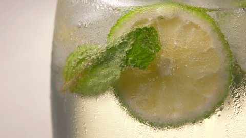 Close-up Glass of cold fizzy refreshing drink with ice cubes. Soda with Ice in glass. Mineral bubbles. 360 rotation. 4K UHD video footage