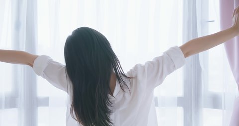 slow motion back view of woman stretching arms after wake up in the morning at home