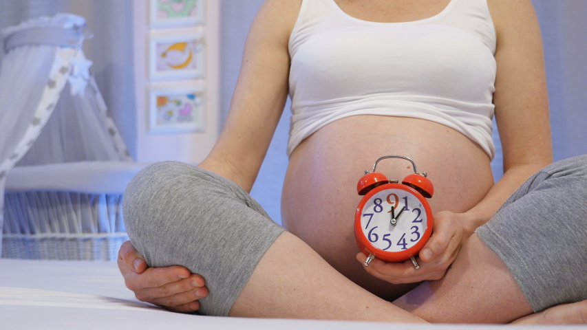Conceptual countdown to delivery, pregnancy month by month. Quickly passing months of pregnancy. A young pregnant woman holds a clock symbolizes nine months of pregnancy. Royalty-Free Stock Footage #1035207494