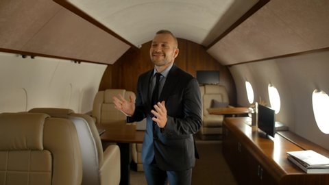 Rich business man dancing inside of luxury jet. Entrepreneur extremely happy of comfortable first class aircraft flight.