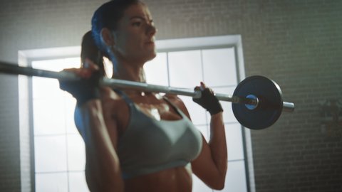 Athletic Beautiful Woman Does Overhead Deadlift with a Barbell in the Gym. Gorgeous Female Professional Bodybuilder Workout Weight Lift Exercises in the Authentic Fit Training Facility. Zoom in