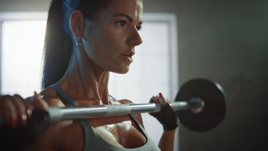 Athletic Beautiful Woman Does Overhead Lift with a Barbell in the Gym. Gorgeous Female Professional Bodybuilder Does Weight Lift Workout Exercises in the Hardcore Training Facility. 4K UHD Royalty-Free Stock Footage #1035217661