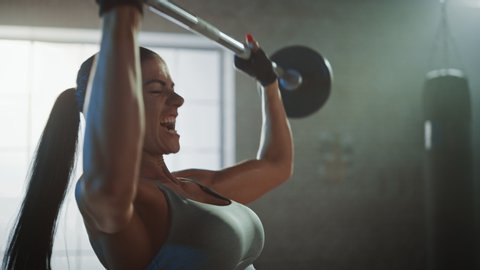 Athletic Beautiful Woman Does Overhead Lift with a Barbell in the Gym. Gorgeous Female Professional Bodybuilder Does Weight Lift Workout Exercises in the Hardcore Training Facility. Zoom in