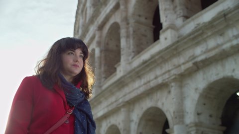 Happy, cheerful Italian woman walking and looking up at the Coliseum. Medium shot on 4k RED camera.