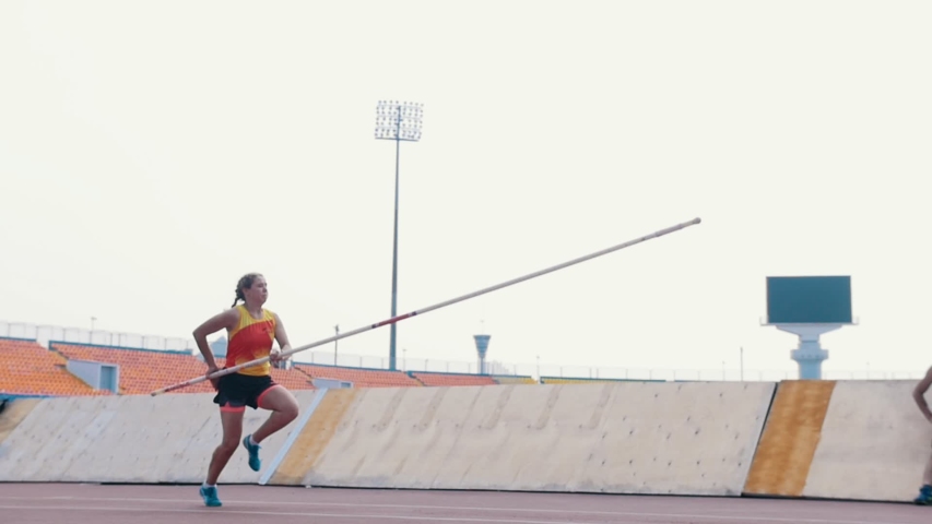 Pole vault training - a woman jumping over the bar - a man watching her