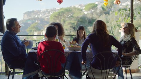 Family enjoying a family meal together outside with view of the Amalfi Coast. 4k RED
